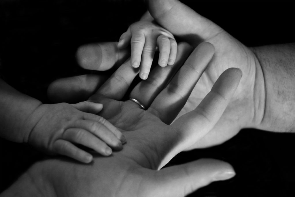 Child's hands placed on palm of parent's hands.
